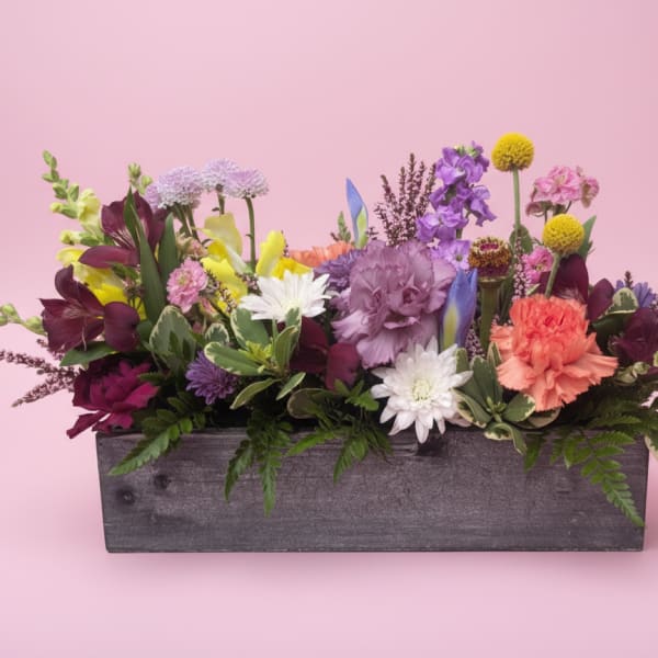 Mixed bouquet in a gray wooden box with purple, pink, white, and yellow flowers