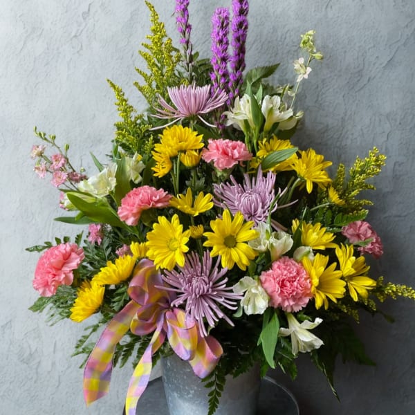 Mixed bouquet of yellow, pink, and lavender flowers in a metal bucket