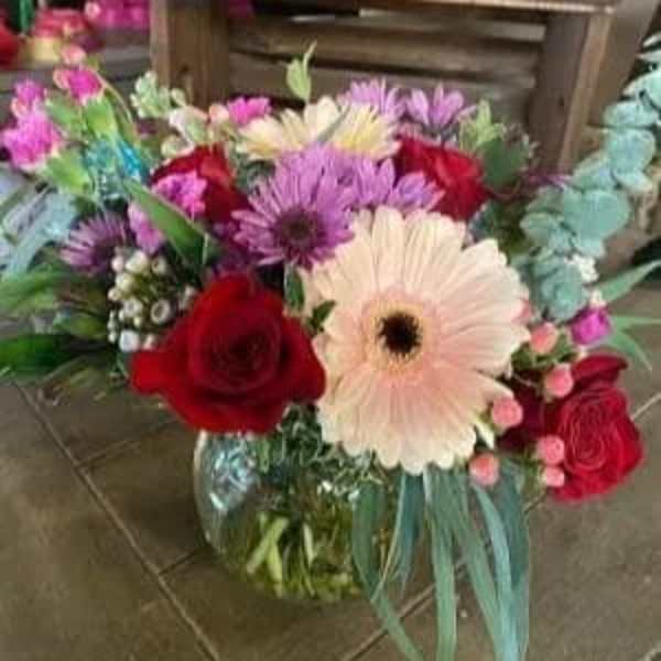 Mixed bouquet with red roses and pink gerbera daisies in a glass vase