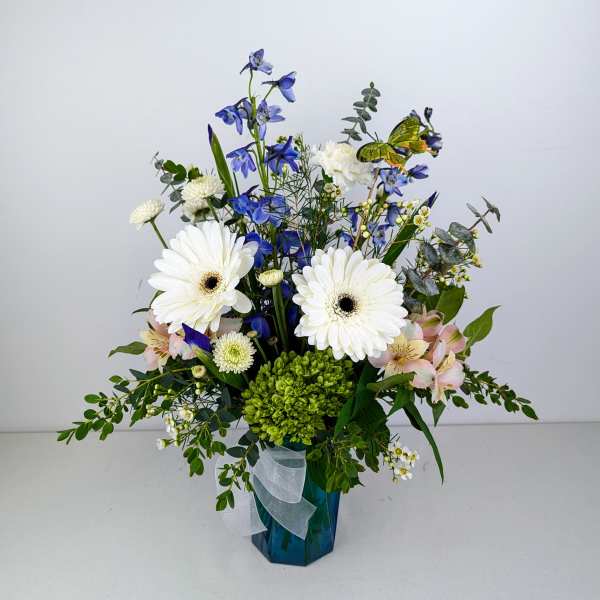 Blue and white floral arrangement in a blue vase with a ribbon