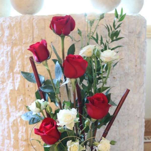 Tall arrangement of red and white roses in a glass vase