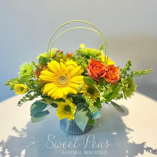 Yellow and orange flower arrangement in a handled container