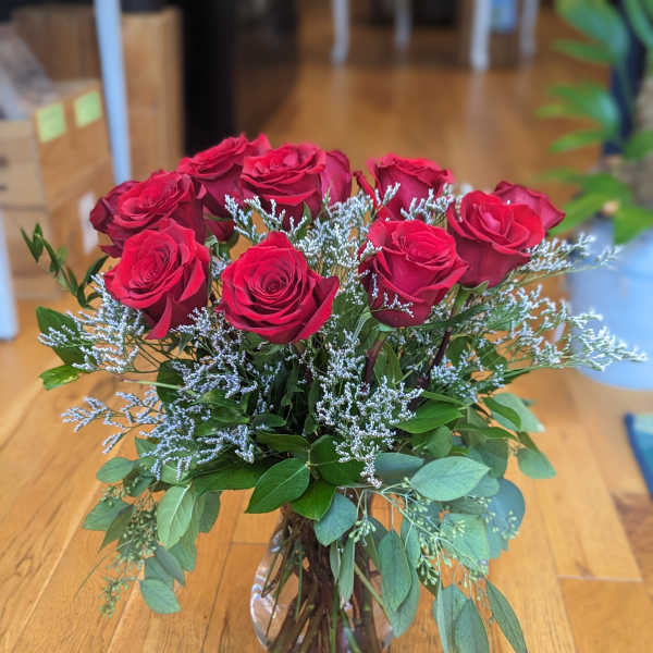 Red roses arranged in a clear glass vase with airy filler and greenery