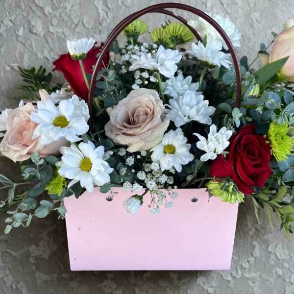 Mixed bouquet of roses and daisies in a pink handled box