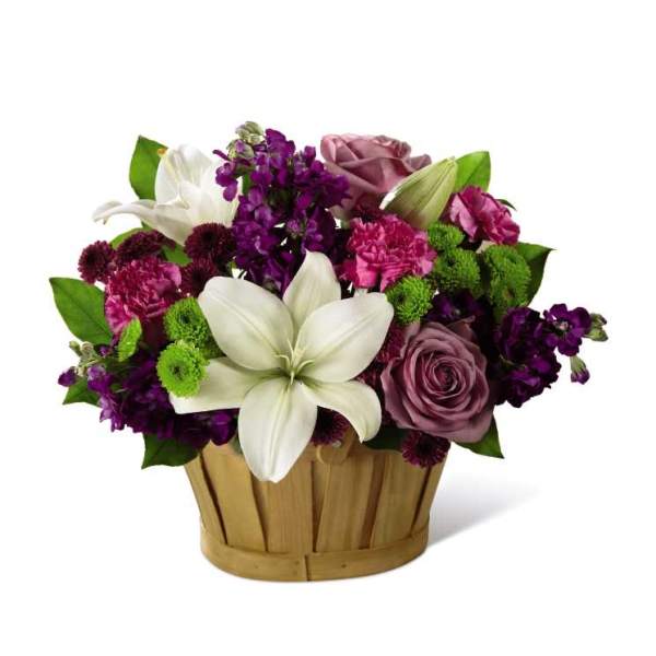 Mixed bouquet in a wooden basket with white lilies and purple flowers