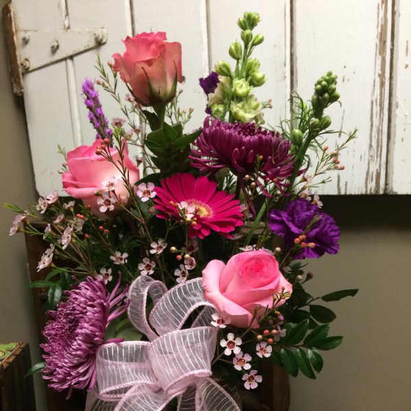 Pink and purple mixed flower arrangement with a ribbon in a glass vase