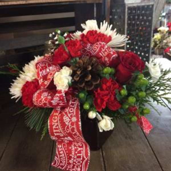 Red and white floral arrangement in a dark vase with a holiday ribbon