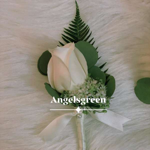 White rose boutonniere with green foliage and a white ribbon