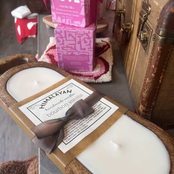 Assorted scented candles in decorative packaging and wooden trays