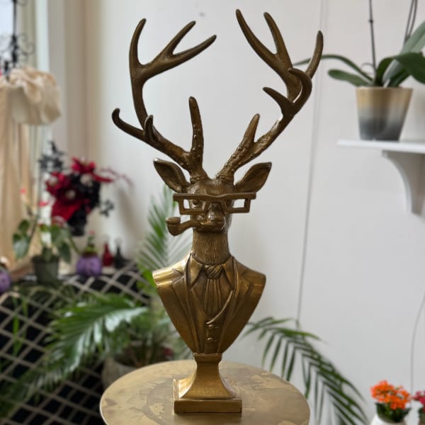 Gold deer bust sculpture with antlers and glasses on a pedestal
