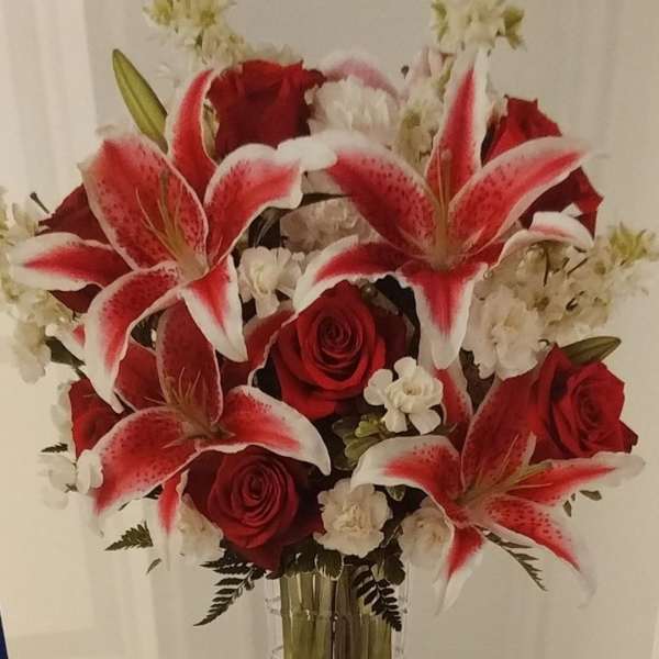 Red roses and white-red lilies in a clear glass vase