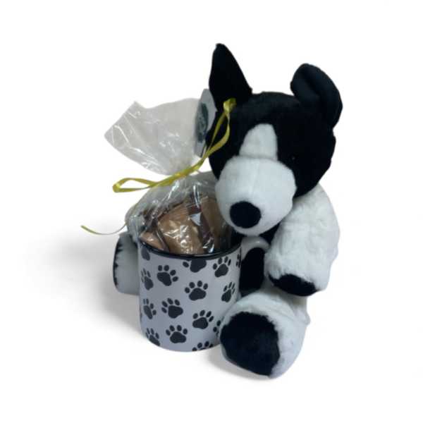Plush dog beside a paw-print mug holding a wrapped gift