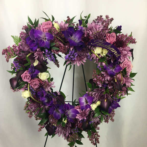Heart-shaped floral wreath with purple and pink flowers on a stand