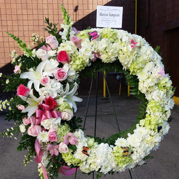 Heart-shaped floral wreath with pink and white flowers on an easel