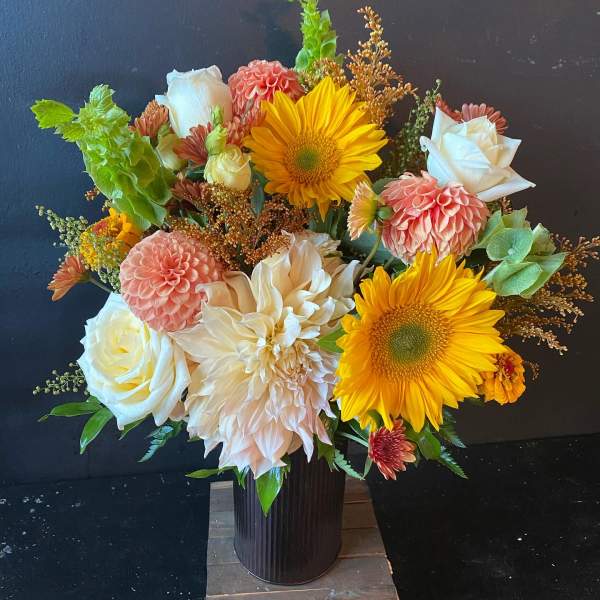 Bouquet of sunflowers, white roses, and peach dahlias in a dark vase