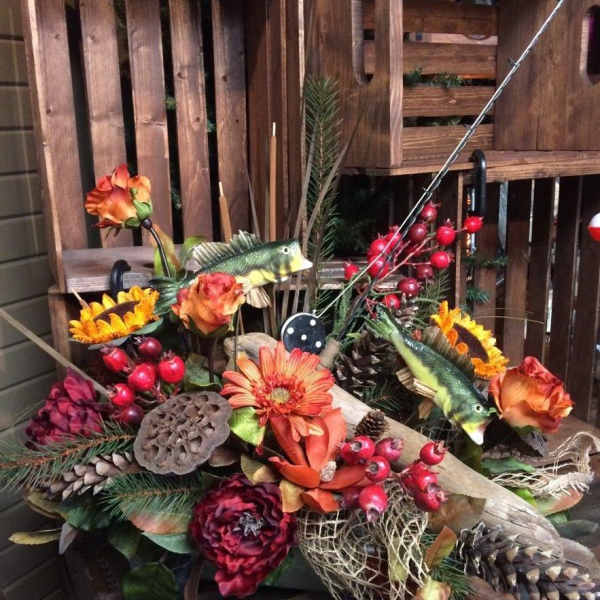 Autumn floral arrangement with orange blooms, berries, pinecones, and fish accents