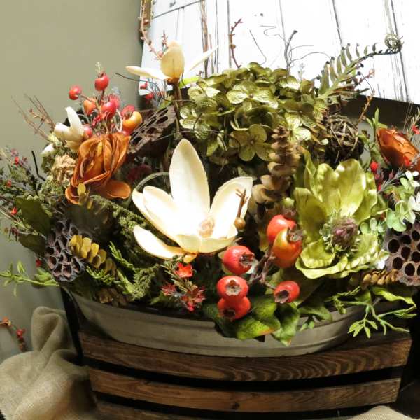 Mixed floral arrangement with white and orange blooms in a wooden container