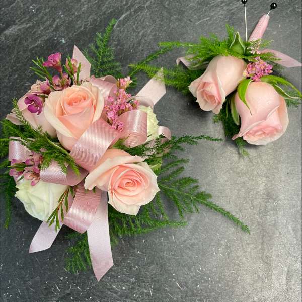 Pink rose corsage and boutonniere with ribbon and greenery