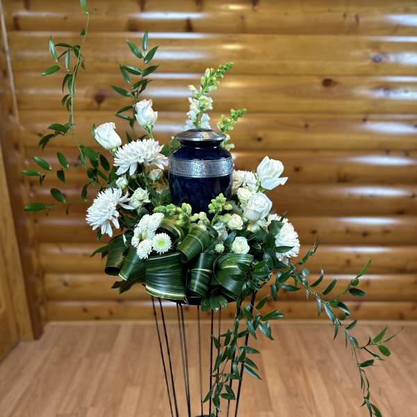 White flowers arranged around a blue urn on a tall stand