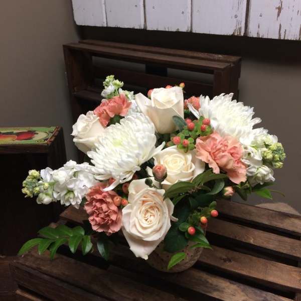 Arrangement of white roses, white chrysanthemums, and pink carnations in a basket