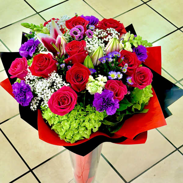 Bouquet of red roses, lilies, and purple flowers in red and black wrap