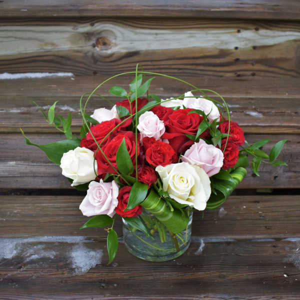 Bouquet of red, white, and pale pink roses in a glass vase