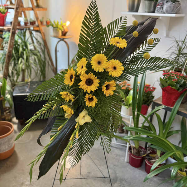 Tall floral standing spray with yellow daisies and tropical leaves