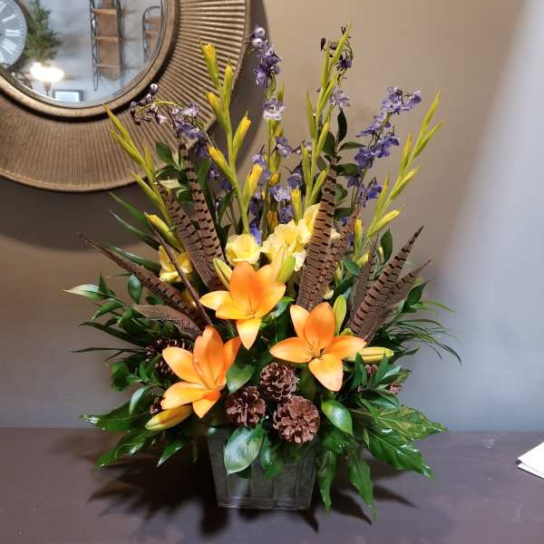 Orange lilies and purple flowers in a square vase