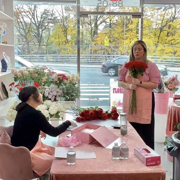 Two women in a flower shop with bouquets and roses on a table
