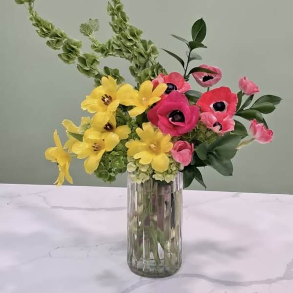 Bright yellow and pink flowers in a clear glass vase