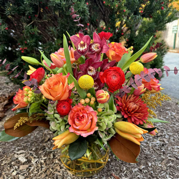 Colorful bouquet with orchids, roses, and tulips in a glass vase
