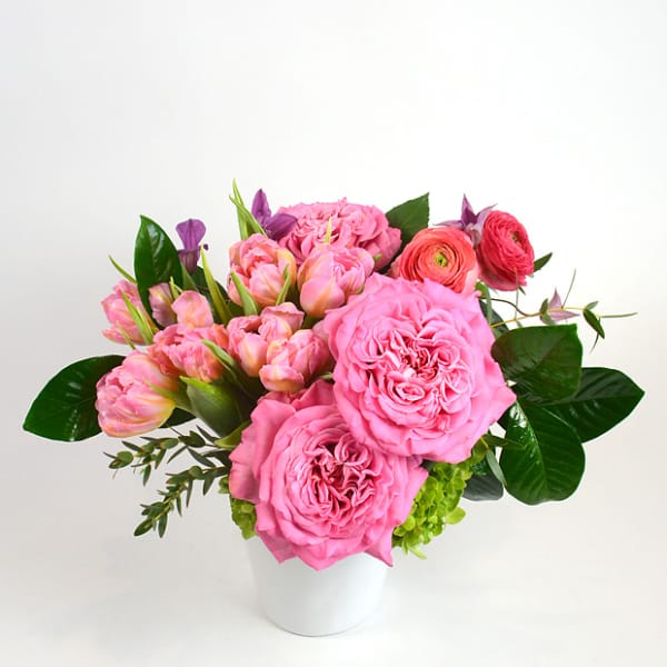 Pink roses and ranunculus arranged in a white vase