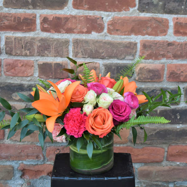 Orange lilies and pink roses in a glass vase