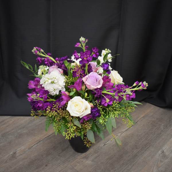 Purple and white mixed flower arrangement in a black vase