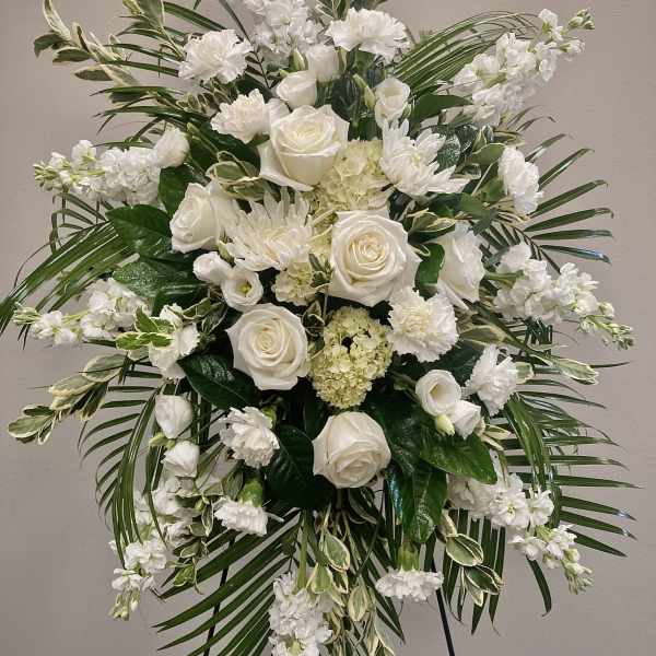 White floral standing spray with roses and carnations on an easel