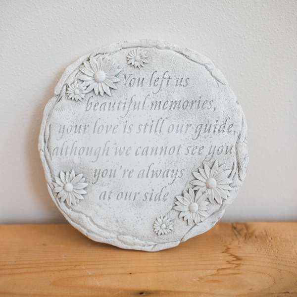 Round memorial plaque with daisy decorations and engraved text