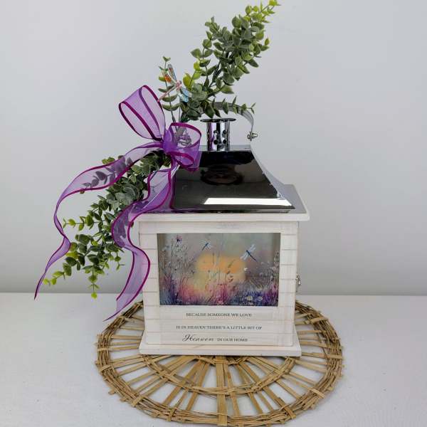 Decorative memorial lantern with greenery and a purple ribbon