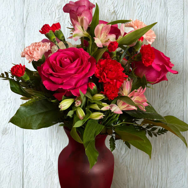 Pink roses and red carnations arranged in a burgundy vase