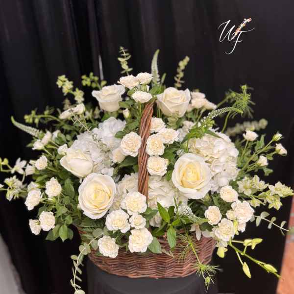 Basket arrangement of white roses and small white blooms