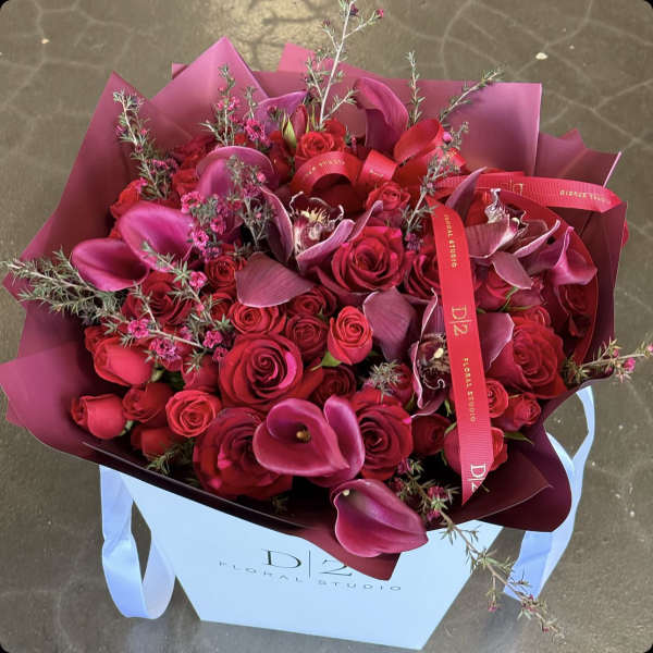 Bouquet of red roses and pink calla lilies in a gift bag