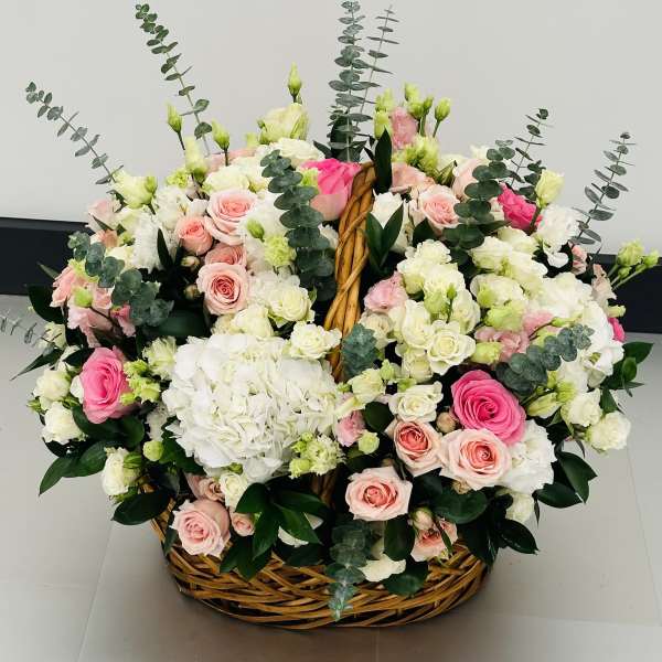 Basket arrangement of pink and white roses with hydrangeas and eucalyptus