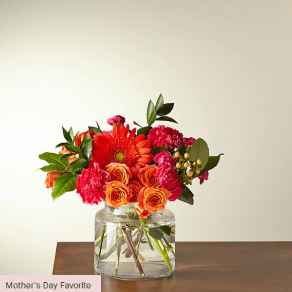 Bouquet of orange and pink flowers in a clear glass vase
