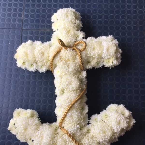 White chrysanthemum cross with gold rope trim on a dark blue background