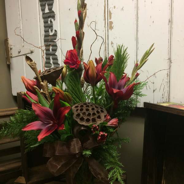 Tall floral arrangement with red lilies and greenery in a vase