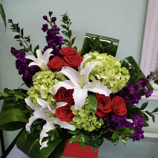Bouquet of red roses, white lilies, and green hydrangeas with purple flowers