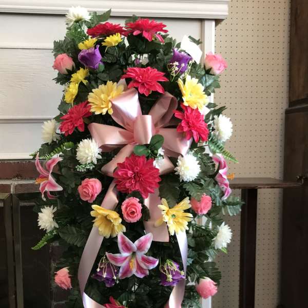 Standing floral spray with pink ribbon and mixed bright flowers