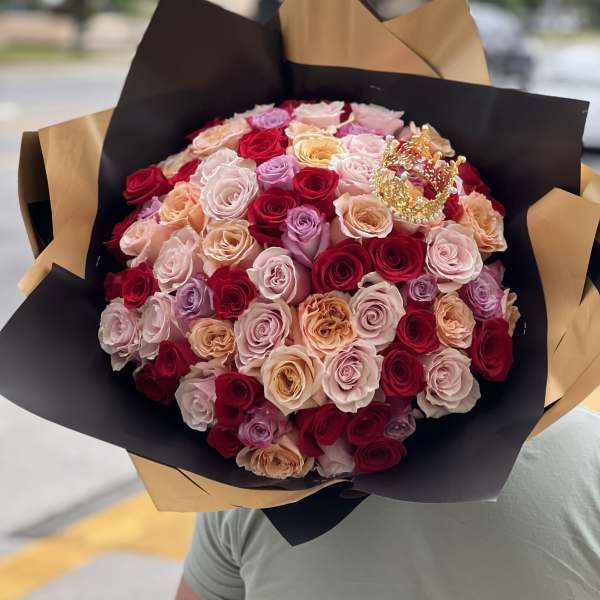 Large bouquet of multicolored roses wrapped in black and gold paper