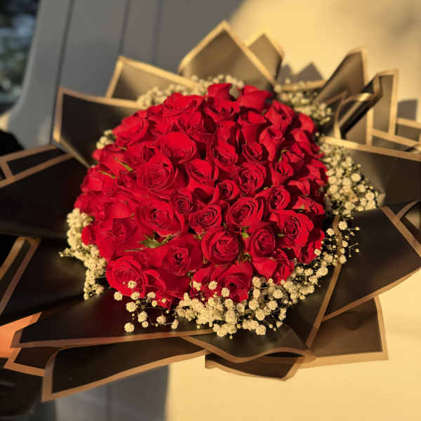Bouquet of red roses with baby's breath in black wrapping