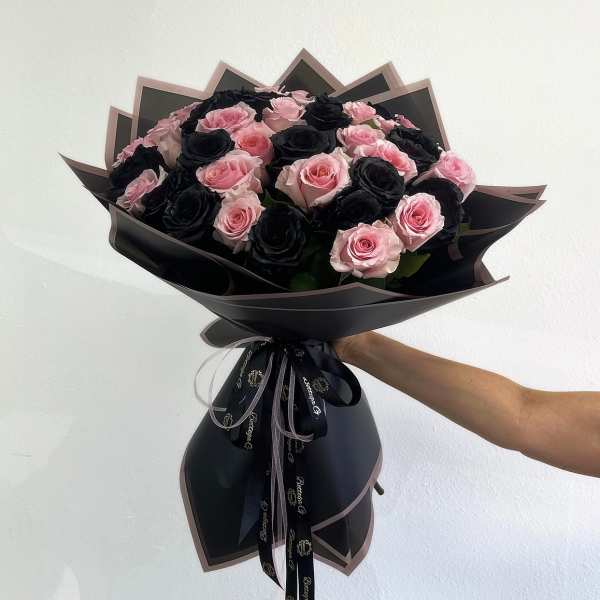 Bouquet of pink and black roses wrapped in black paper