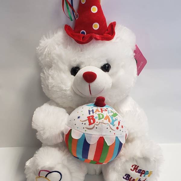White teddy bear wearing a red birthday hat and holding a birthday cake